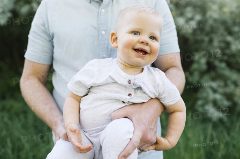 Outdoor portrait of baby boy carried by his father outdoors