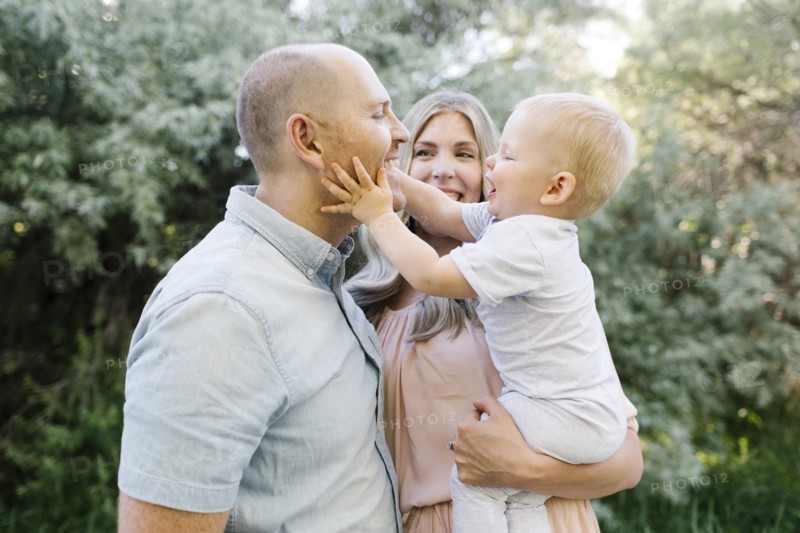 Happy parents standing in garden with baby son