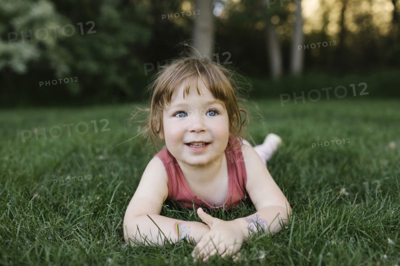Girl (2-3) lying on grass