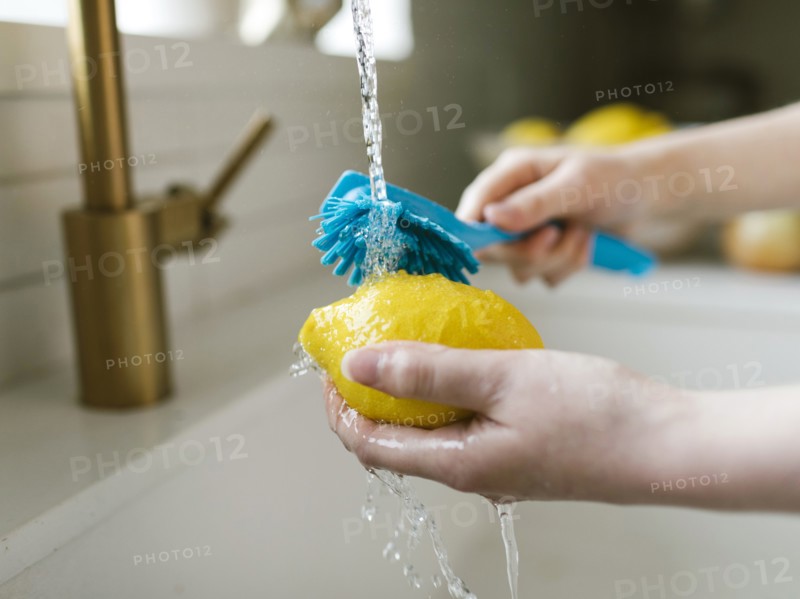 Woman washing lemon with brush