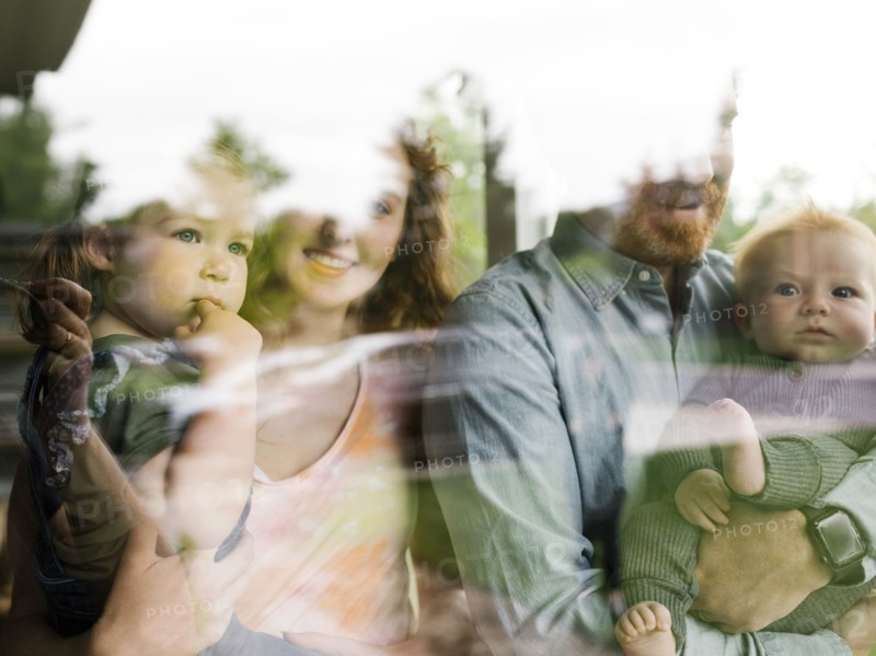 Family with children (6-11 months, 2-3) looking through window,