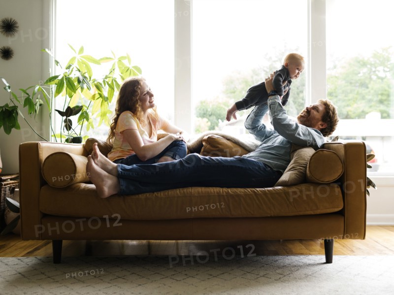 Mother and father playing with baby son (6-11 months) on sofa