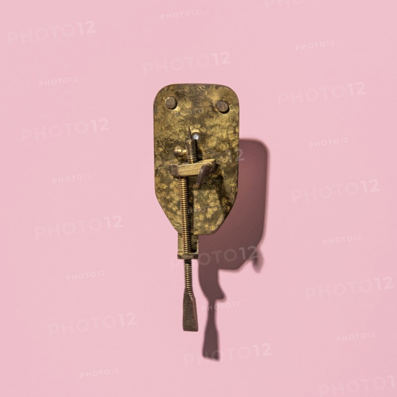 Antique Leeuwenhoek microscope on a pink background