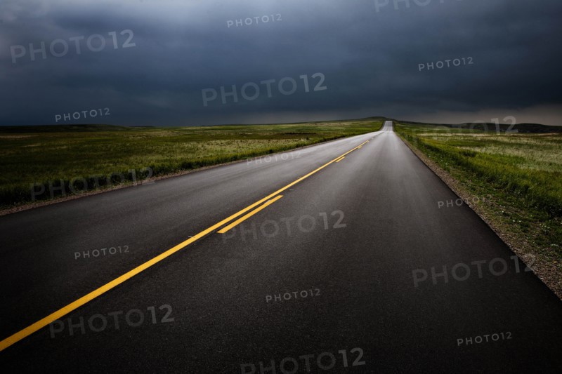USA, South Dakota, Badlands National Park, Storm clouds over road in prairie