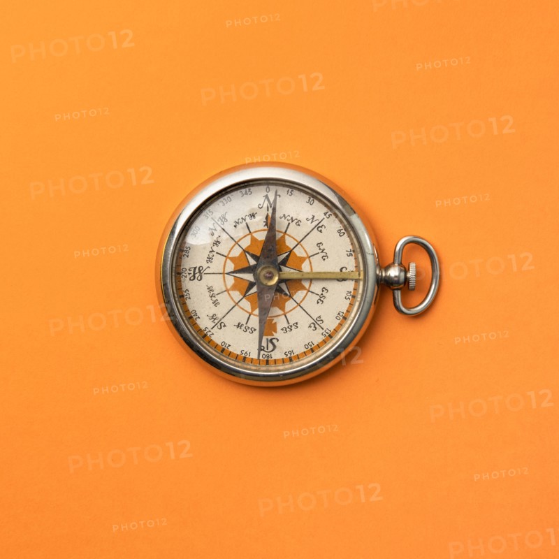 Antique compass on orange background