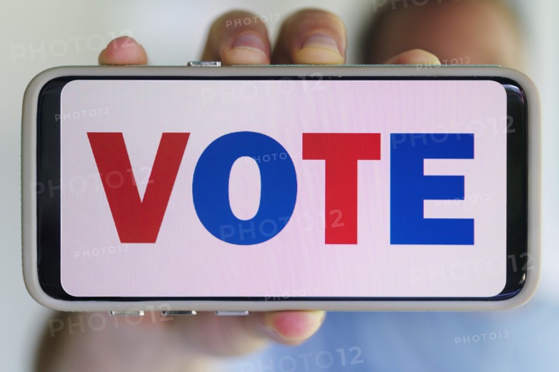 Hand holding smartphone with voting message