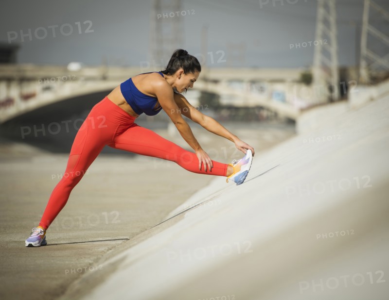 USA, California, Los Angeles, Sporty woman stretching in urban setting