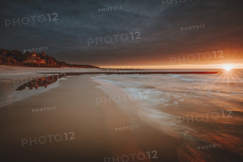 Poland, Pomerania, Leba, Baltic Sea coastline with distant town at sunset