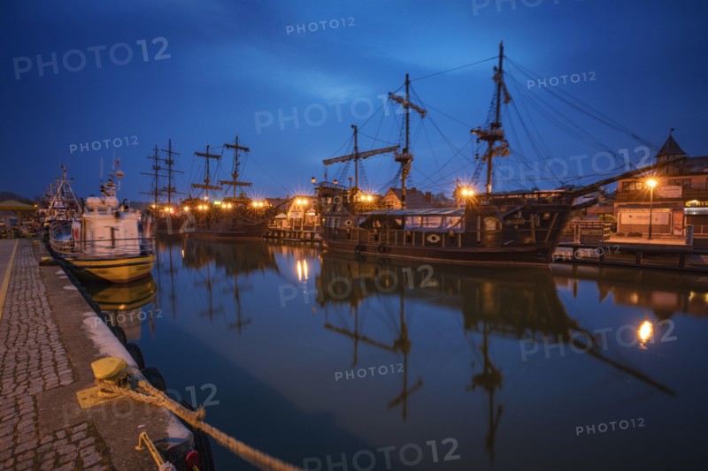 Poland, Pomerania, Leba, Historic tall ships moored at harbour at dusk