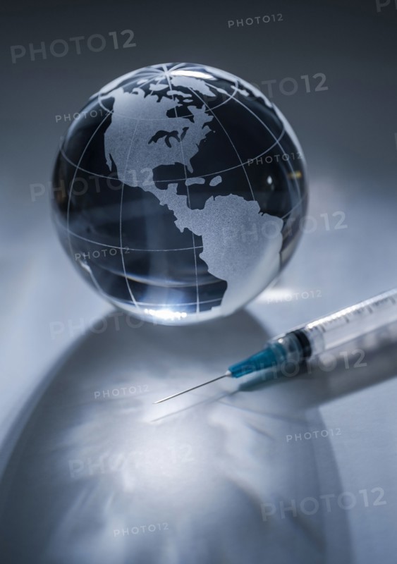 Glass globe and syringe on gray background