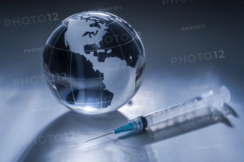 Glass globe and syringe on gray background