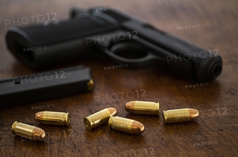 Gold bullets and pistol on wooden surface