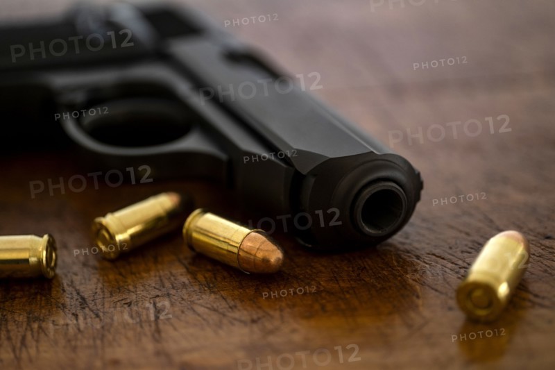 Gold bullets and pistol on wooden surface