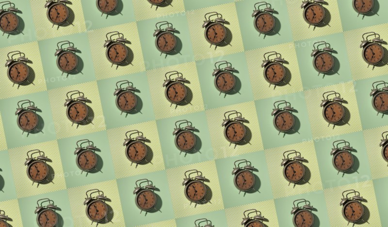 Rows of vintage alarm clocks on green background