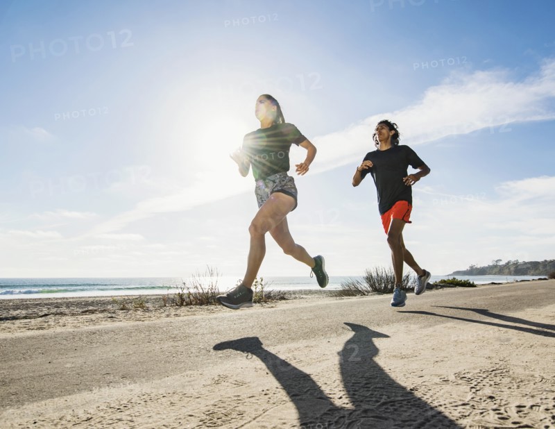 USA, California, Dana Point, Man and woman running together by coastline