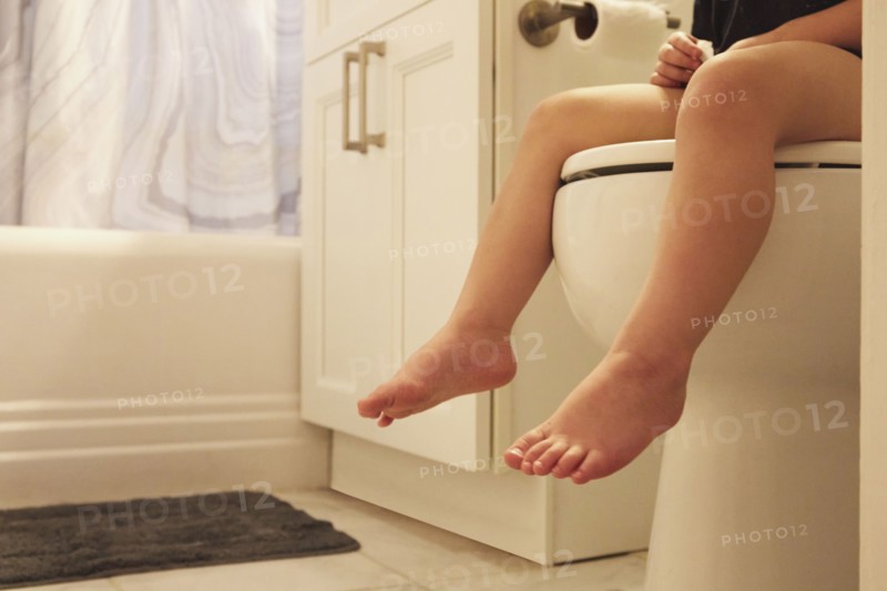 Legs of toddler girl (2-3) sitting on toilet seat
