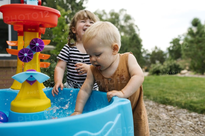 Toddler girl (2-3) and baby boy (18-23 months) playing in garden