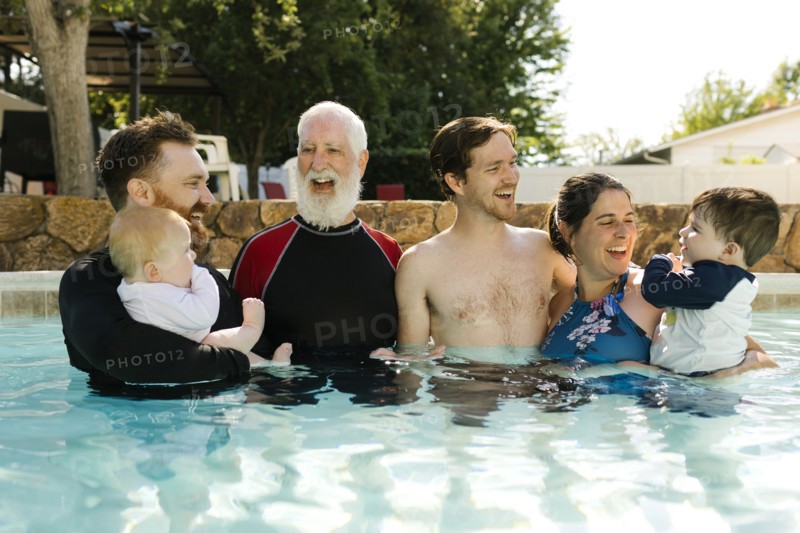 Multigeneration family with kids ( 2-3, 6-11 months) standing in outdoors swimming pool