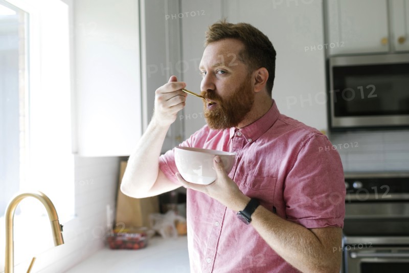 Man eating cereal breakfast in kitchen