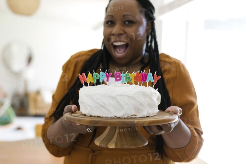 Portrait of smiling woman holding birthday cake with candles