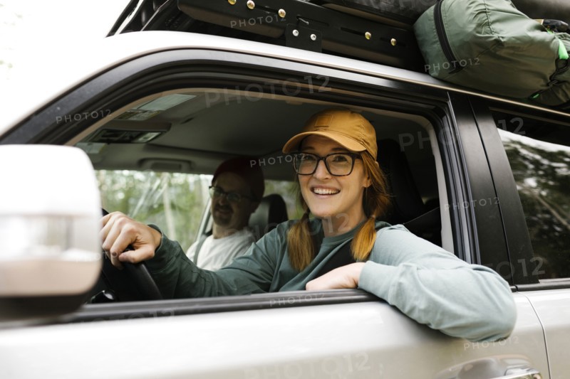 Woman and man sitting in off road car with tent on roof