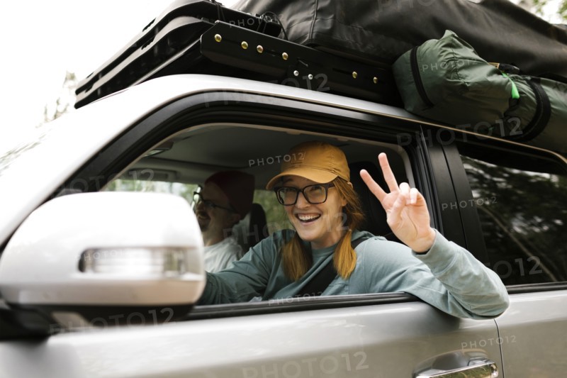 Woman and man sitting in off road car with tent on roof