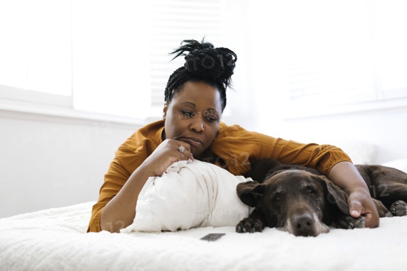 Sad woman lying on bed with dog