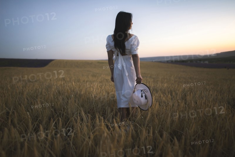 France, Young woman in white dress standing in cereal field