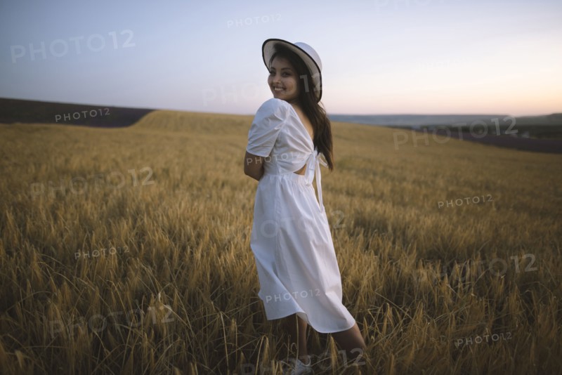 France, Young woman in white dress standing in cereal field