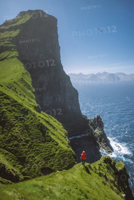 Denmark, Faroe Islands, Klaksvik, Trollanes, Woman standing on cliff and looking at ocean