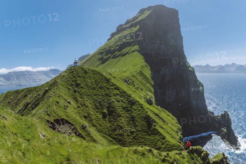 Denmark, Faroe Islands, Klaksvik, Trollanes, Woman standing on cliff and looking at Kallur Lighthouse