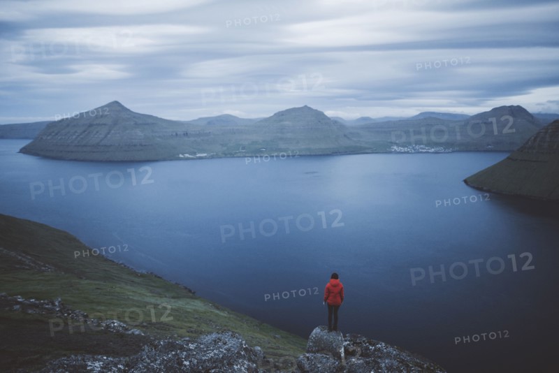 Denmark, Faroe Islands, Klaksvik, Woman standing on rock and looking at fjord