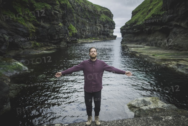 Denmark, Faroe Islands, Gjgv, Man standing inn gorge with outstretched arms
