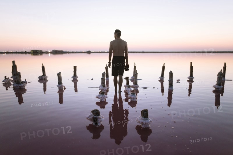 Ukraine, Crimea, Man standing in salt lake and holding camera