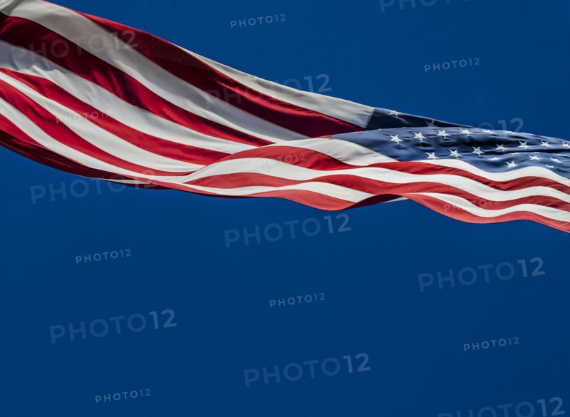 American flag blowing in wind against blue sky