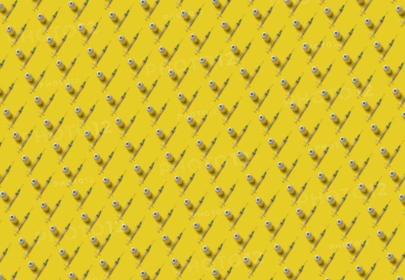 Rows of laboratory vials and syringes on yellow background