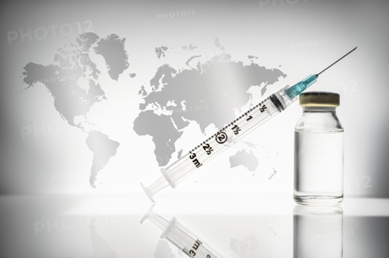 Studio shot of laboratory vial and syringe with world map in background