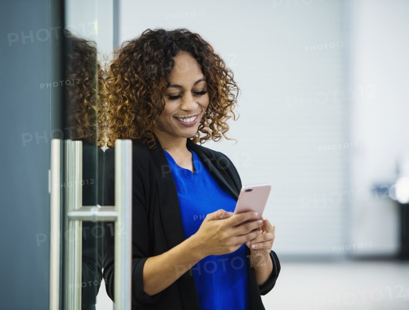 Smiling businesswoman using smart phone in office