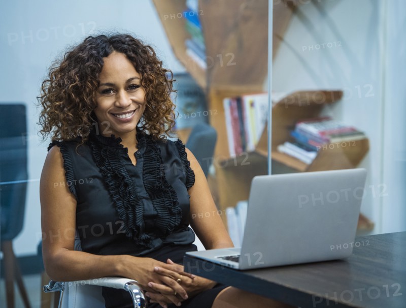 Portrait of smiling businesswoman sitting at desk in office