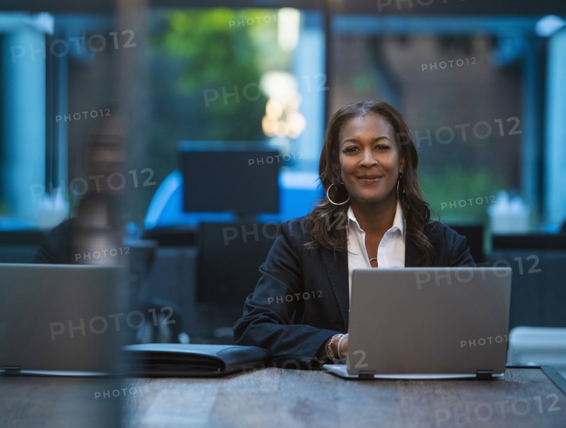 Portrait of smiling businesswoman sitting at desk with laptop in office
