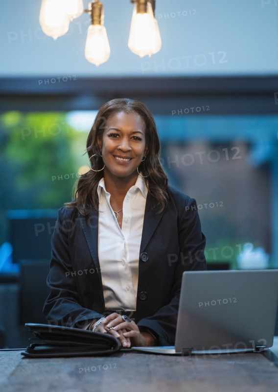 Portrait of smiling businesswoman sitting at desk with laptop in office