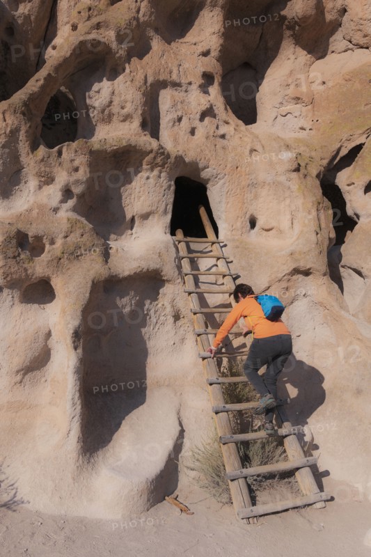 Woman climbing ladder to cliff dwellings in Bandelier National Monument