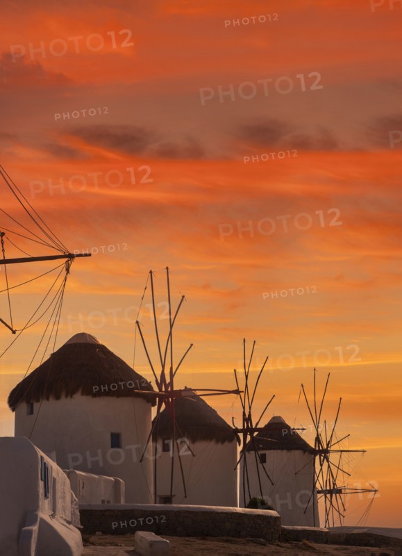 Whitewashed windmills against sunset sky