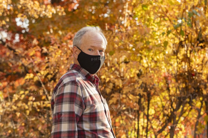 Portrait of senior man wearing Covid protective mask outdoors in fall