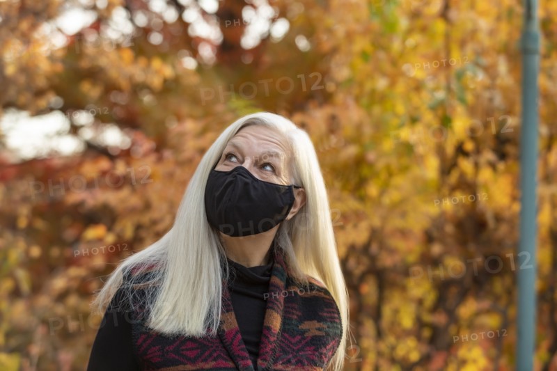 Portrait of senior woman wearing Covid protective mask outdoors in fall
