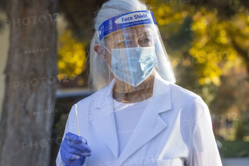 Female medical staff in protective clothing holding coronavirus swab test outdoors