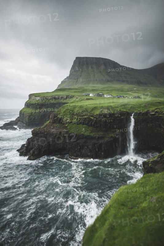 Coastline with Mulafossur Waterfall falling into Atlantic Ocean