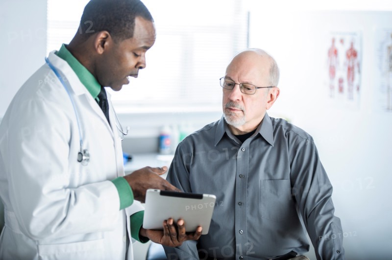 Doctor with digital tablet talking to patient
