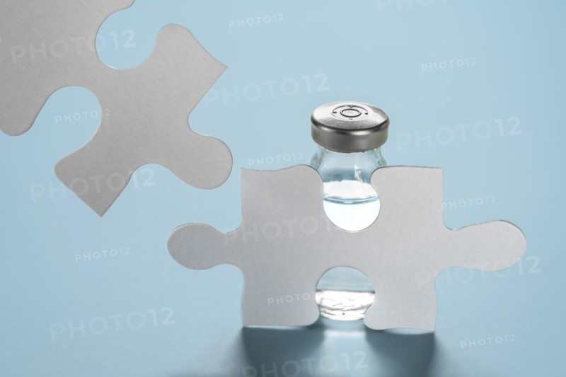Vial of Covid-19 vaccine behind jigsaw puzzles
