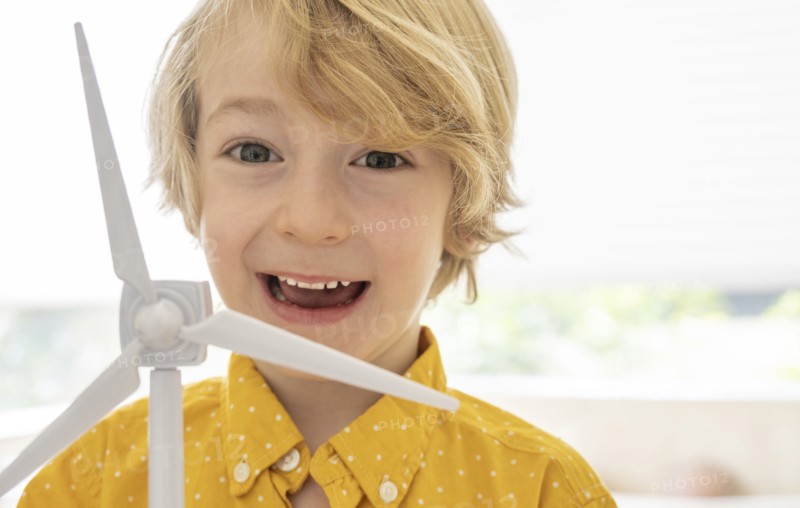 Portrait of smiling boy (6-7) with wind turbine model